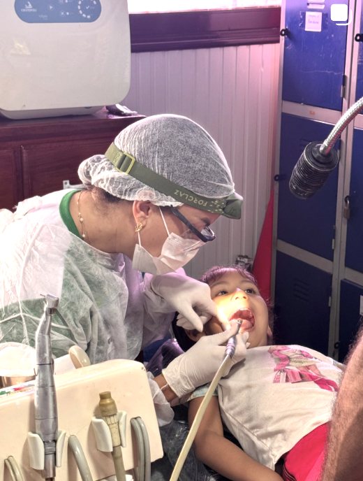 Dra. Laís Simas atendendo uma criança com carinho em cadeira odontológica